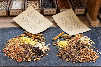 Plantas secas, raíces y cortezas sobre un mostrador de una herboristería tradicional china.