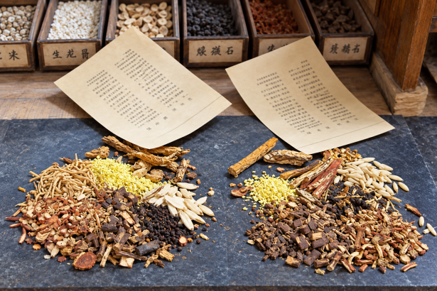 Plantas secas, raíces y cortezas sobre un mostrador de una herboristería tradicional china.